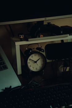 A cozy home workspace featuring an analog clock, laptop, and gaming equipment, perfect for productivity.