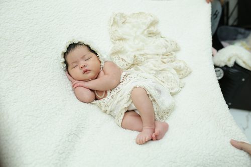 Free A cute newborn baby sleeps peacefully wrapped in a delicate lace blanket. Stock Photo