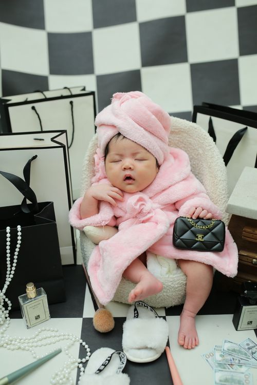 Free Adorable baby in a pink robe surrounded by luxury items, adding a touch of elegance. Stock Photo