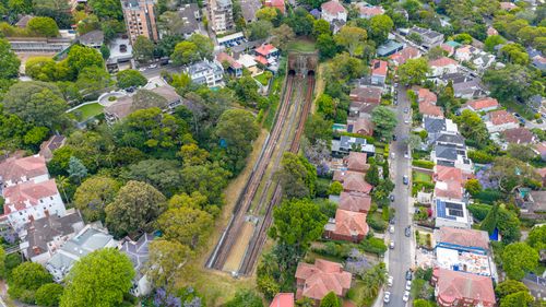 Free Aerial image capturing a Sydney suburb with green trees, residential houses, and visible train tracks. Stock Photo