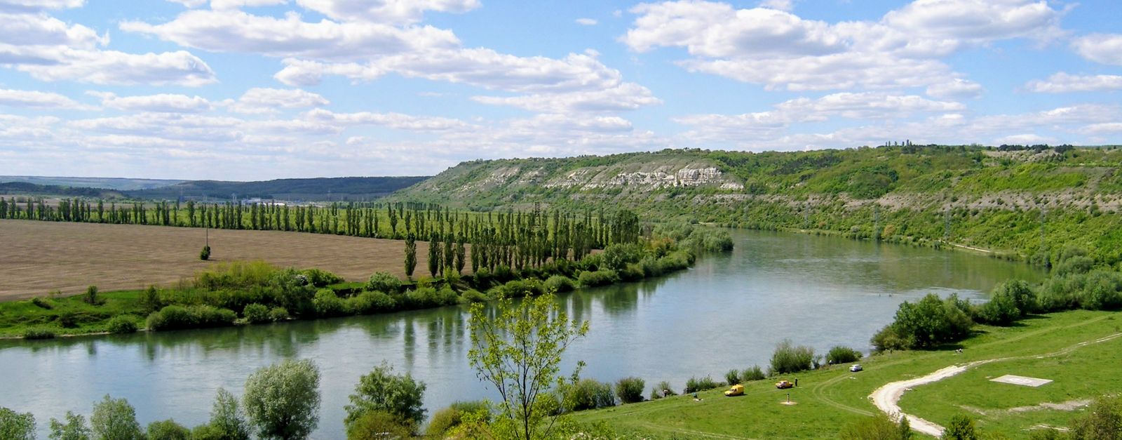 A winding river flows through a green landscape under a bright blue sky.