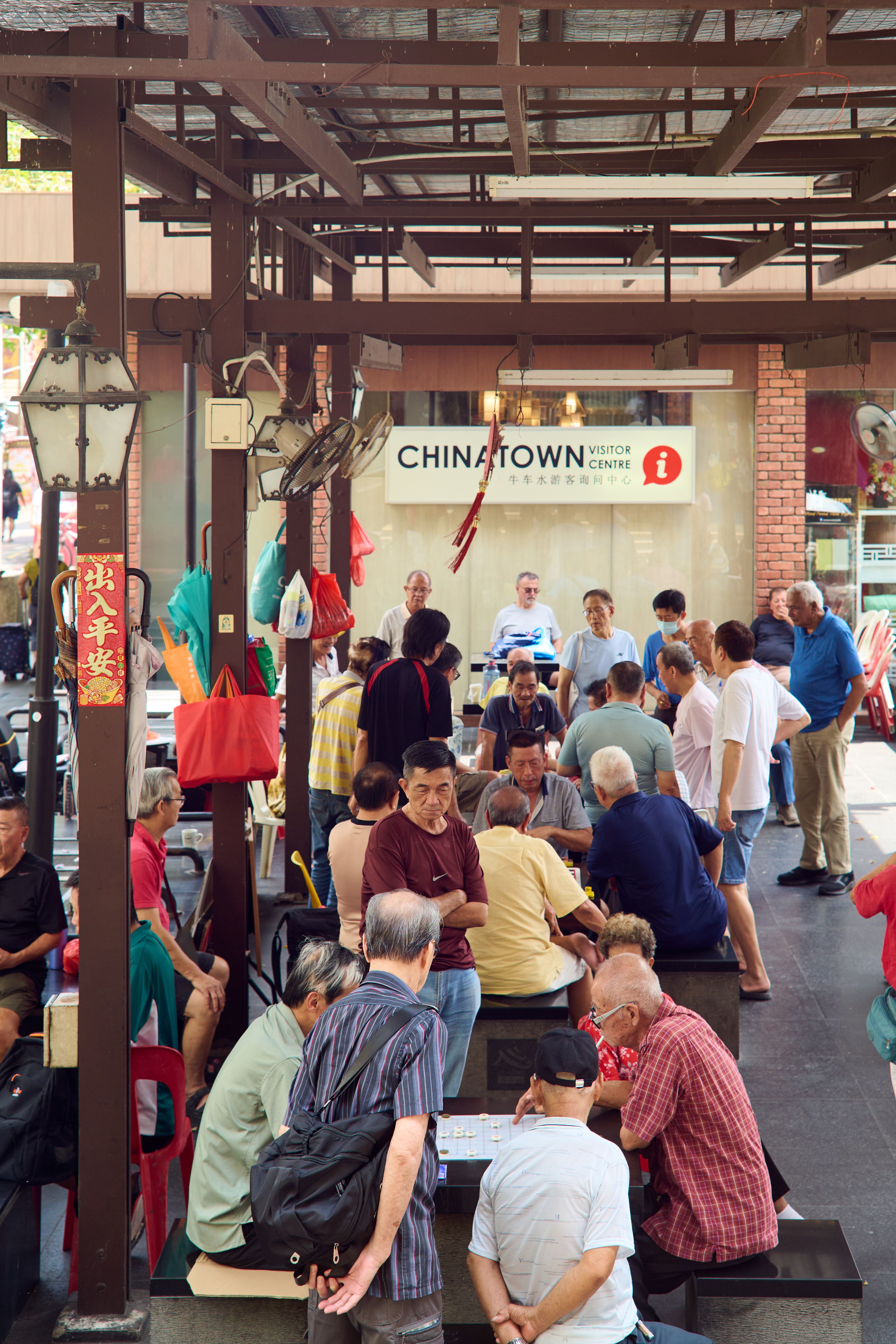 Busy lunchtime scene inside Maxwell Food Centre hawker centre in Chinatown, Singapore, with trays of local dishes