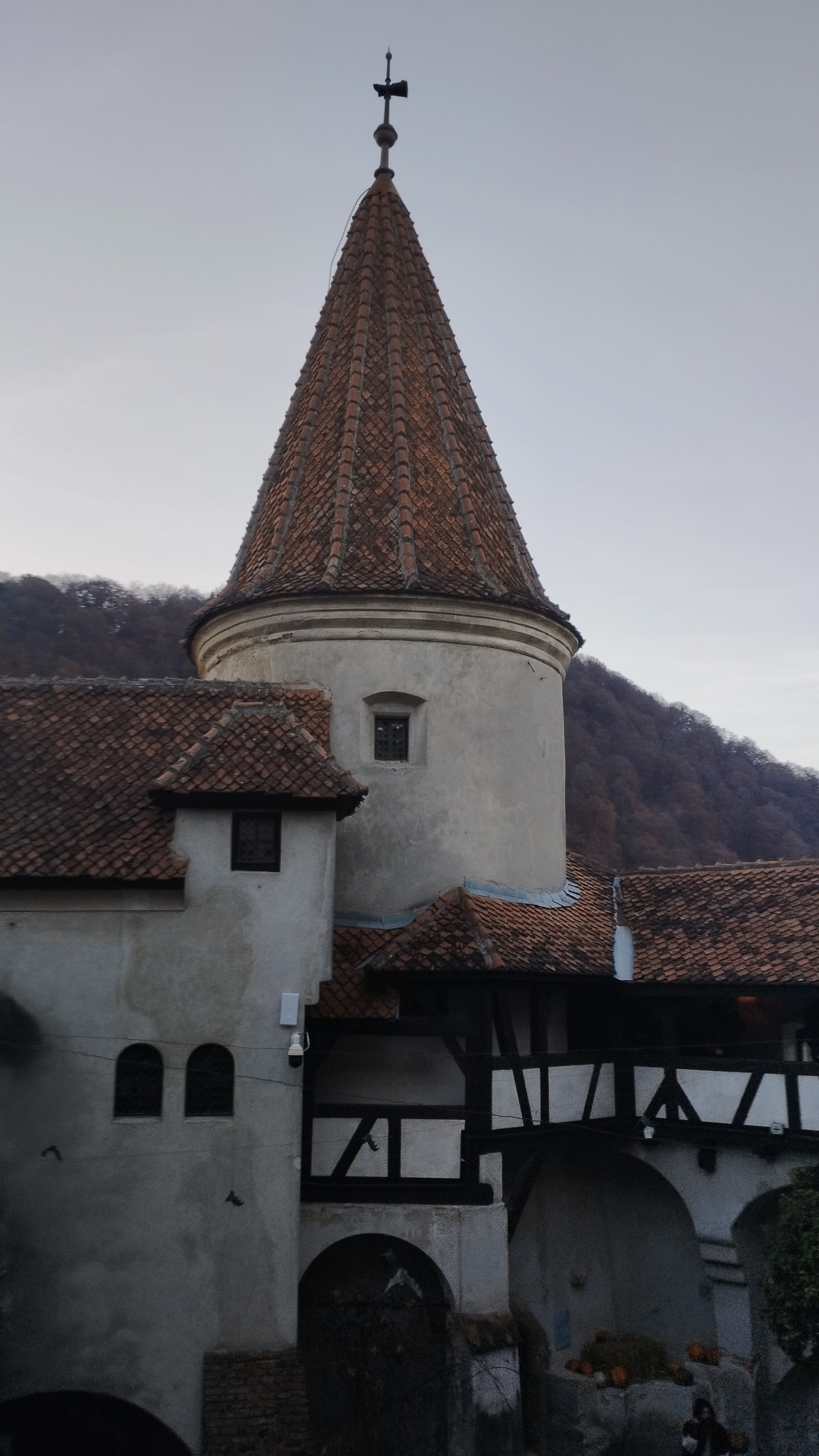 A scenic view of a historic medieval castle tower with a mountain backdrop at dusk.
