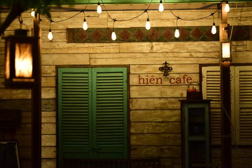 Free Cozy rustic cafe facade adorned with warm string lights and wooden shutters. Stock Photo