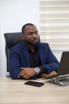 African businessman working on a laptop in a modern office setting.