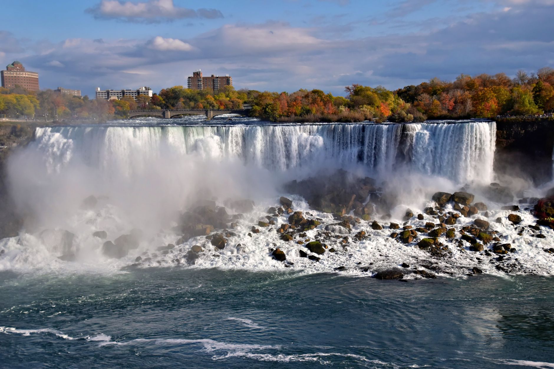 Majestic view of Niagara Falls with vibrant autumn foliage and mist in Ontario, Canada.