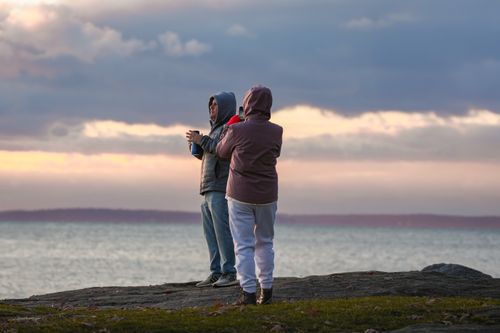 Free Couple viewing the sunrise at Cove Island Park, Stamford, CT, with a scenic ocean backdrop. Stock Photo