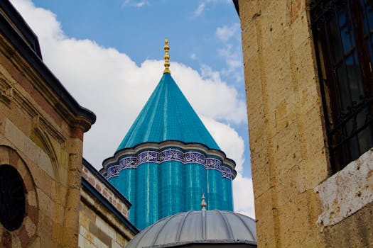 The iconic blue-tiled dome of Mevlana Museum captured against a bright sky in Konya, Turkey.