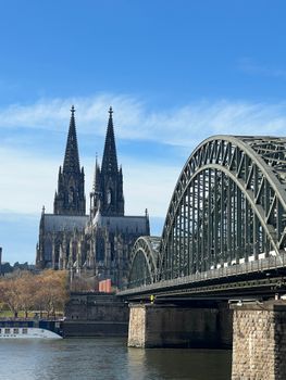 Iconic view of Cologne Cathedral and the Hohenzollern Bridge with a clear blue sky.
