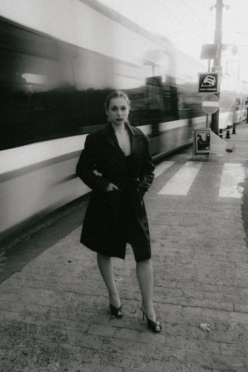 Free Stylish woman poses against a blurred train, showcasing city life. Stock Photo