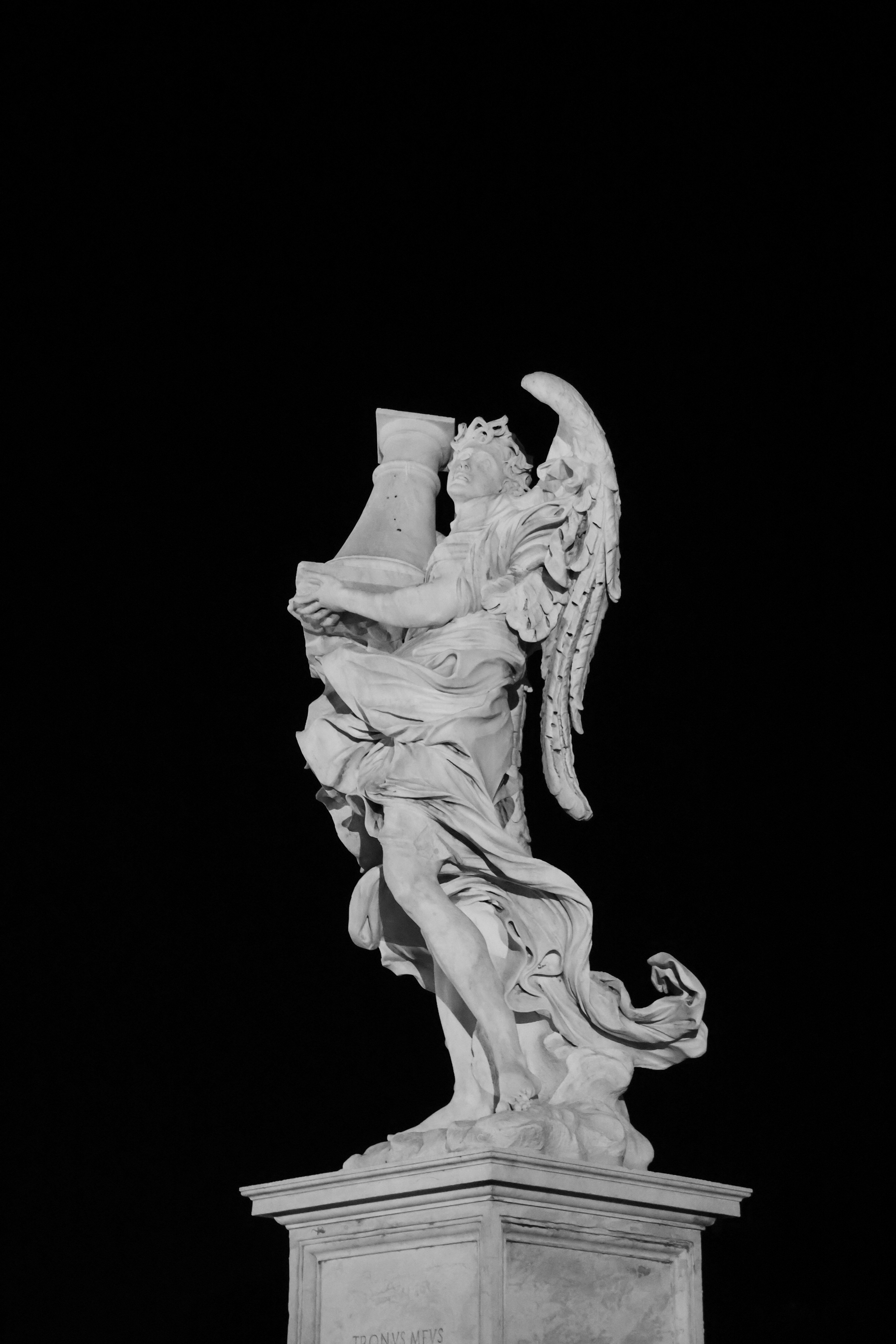 Monochrome photo of a majestic angel statue against dark sky in Rome.