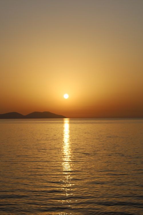 Free Tranquil sunset view over the ocean with a golden reflection, creating a serene and peaceful atmosphere. Stock Photo