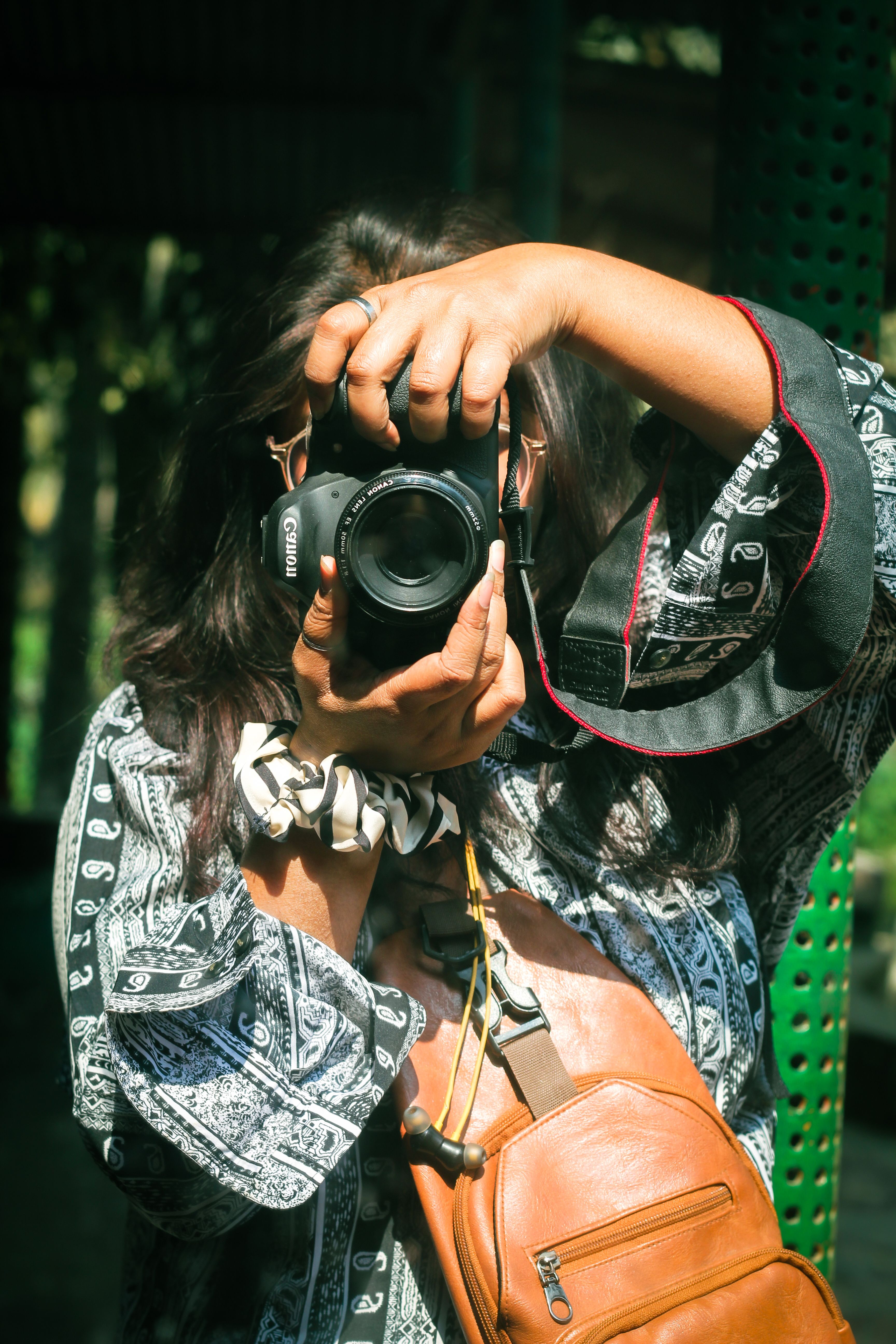A young woman in Dhaka using a camera outdoors, capturing vibrant scenes of the city.