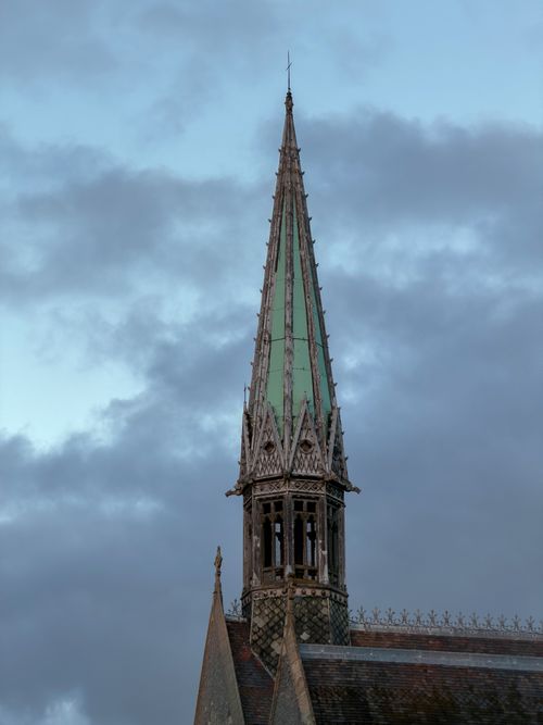 Free Dramatic view of the Gothic Revival spire of Harrow School Chapel set against a cloudy sky. Stock Photo