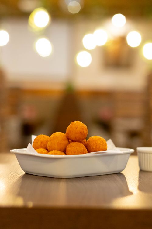 Free Golden cheese balls served in a rustic indoor setting with warm lighting. Stock Photo