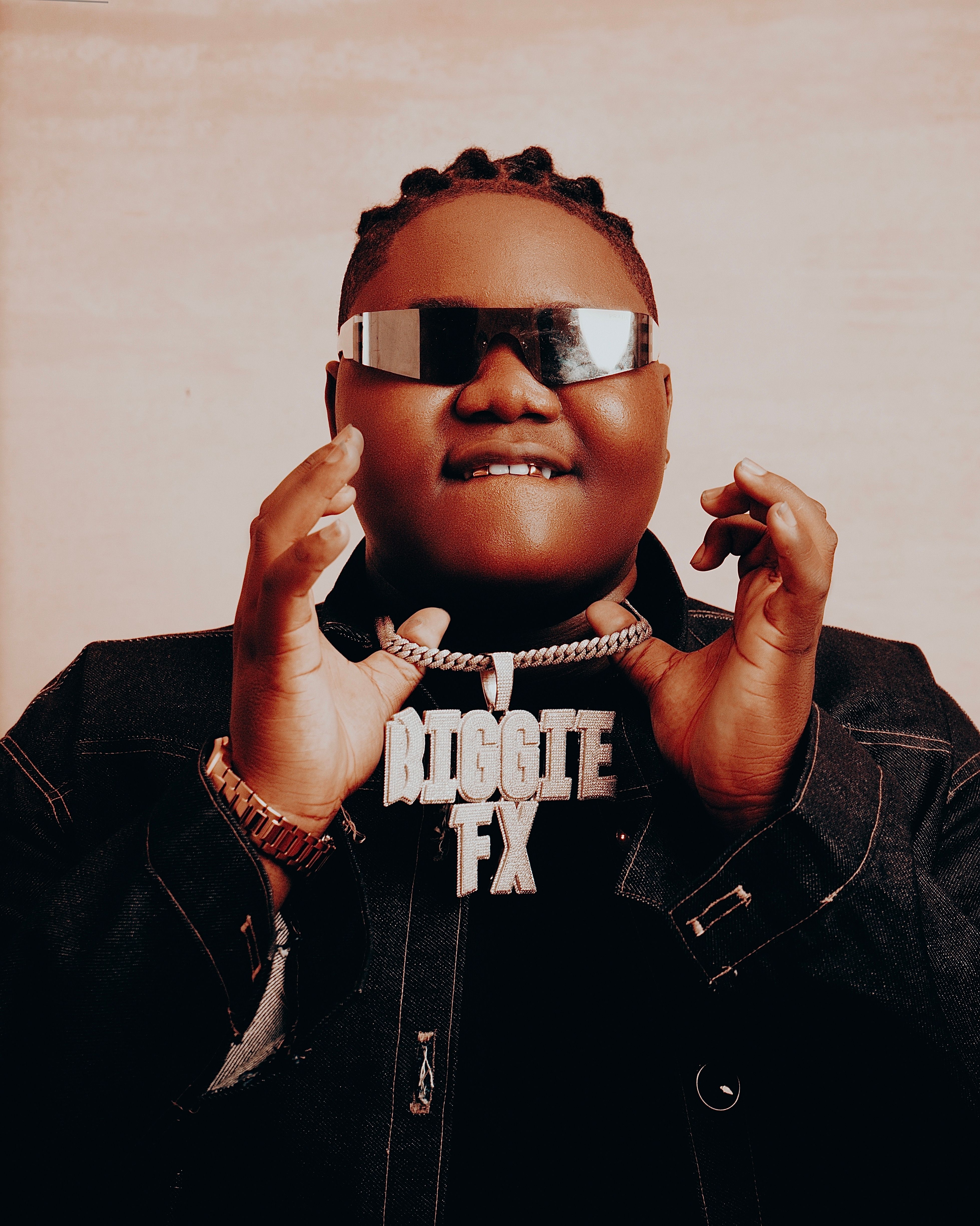 A trendy adult poses with sunglasses and a statement necklace.