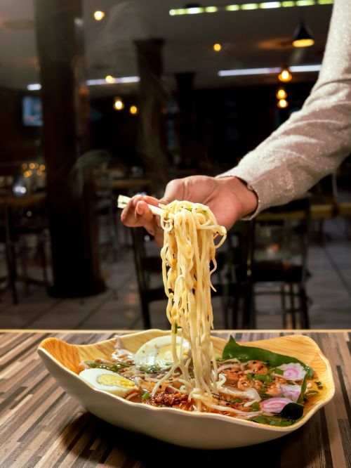 Free A stylish bowl of noodle soup with toppings in a cozy, modern restaurant. Stock Photo