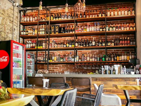 Cozy restaurant bar with industrial design and diverse beverage selection, ideal for dining ambiance.