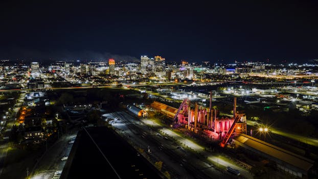 Stunning aerial view of Birmingham, Alabama skyline at night featuring the illuminated Sloss Furnaces.