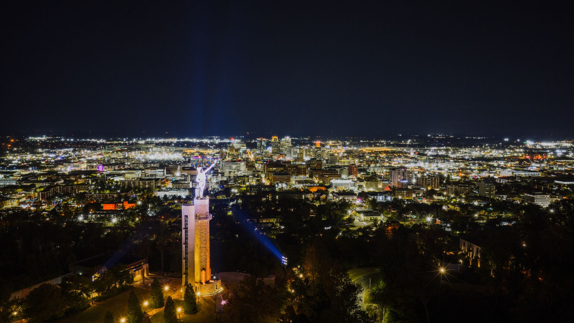 Aerial view of Birmingham's nighttime skyline featuring the iconic Vulcan statue.