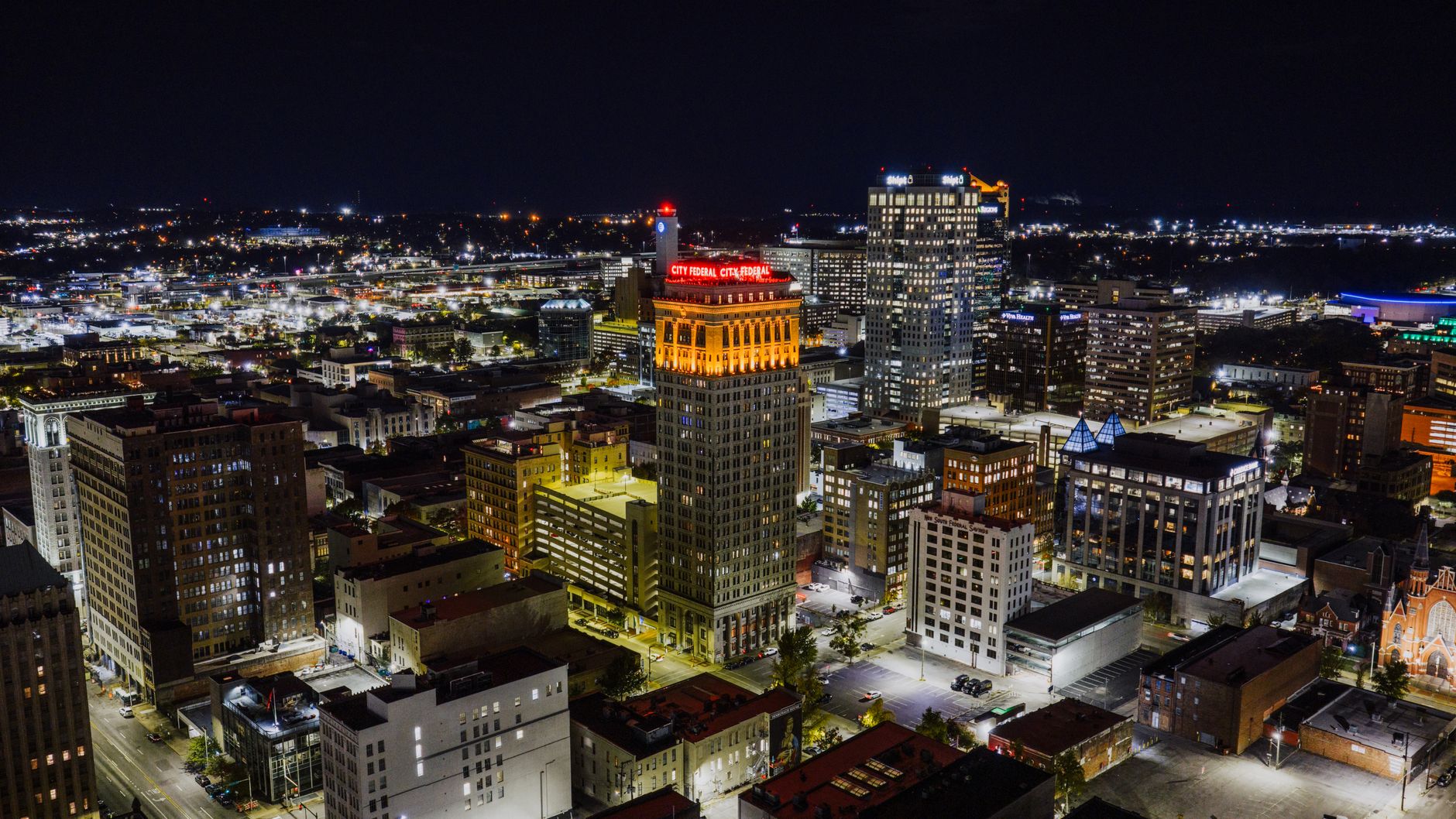 Stunning aerial view of Birmingham, Alabama at night showcasing the illuminated cityscape with prominent landmarks.