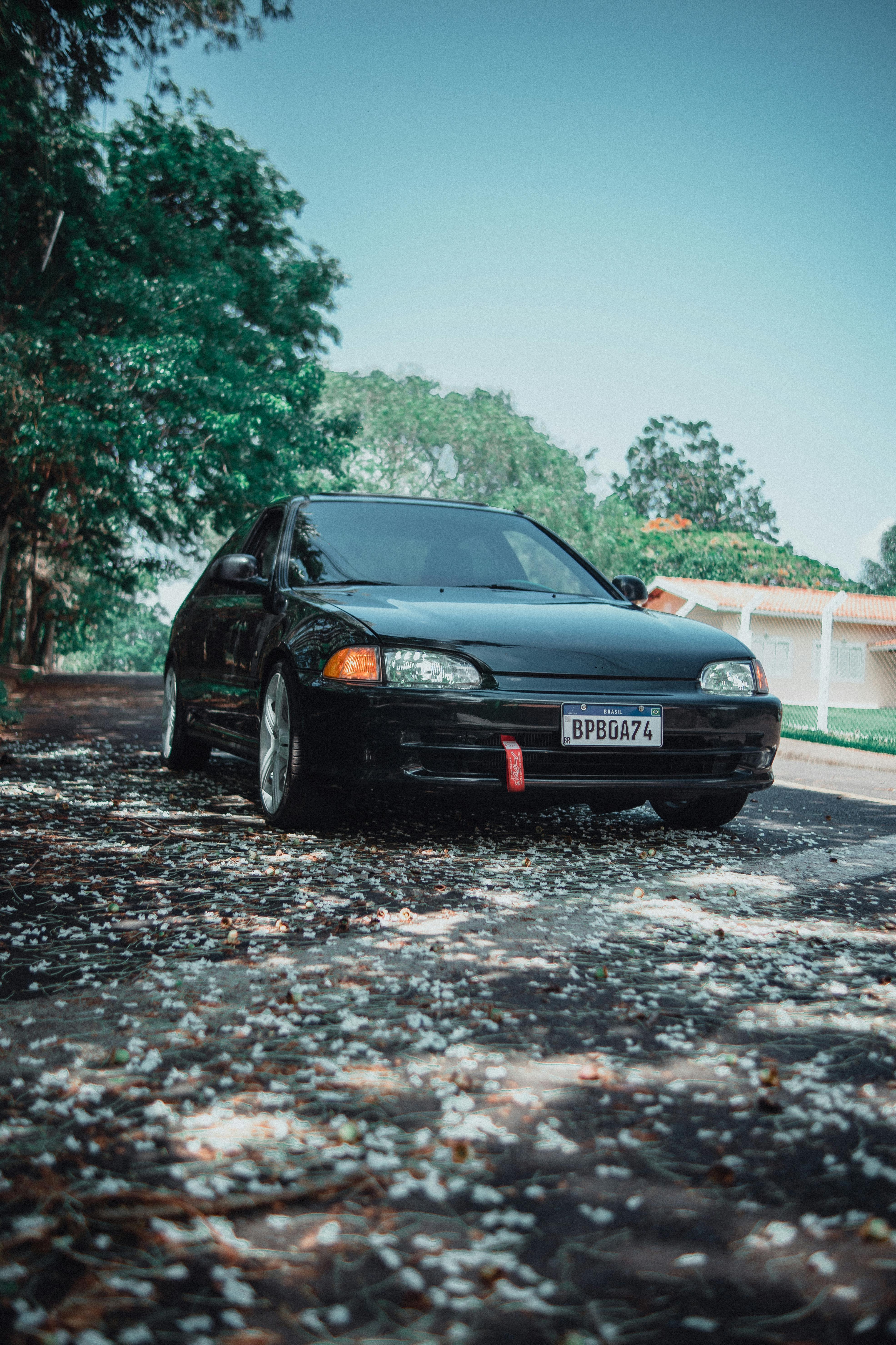 Free A sleek black car parked on a leaf-covered road under a clear blue sky in Brazil. Stock Photo