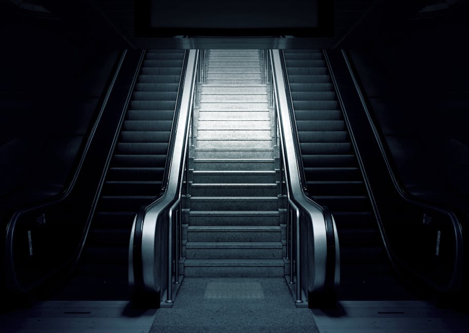 Grey and Black Escalator on Dimmed Place. Advice on taking the stairs and getting Fitness Success in 2019!