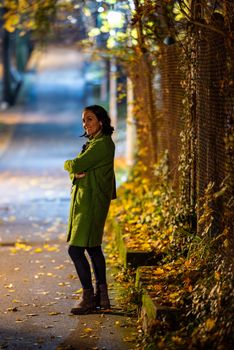 A woman enjoys a peaceful autumn evening walk on a tree-lined street, captured with cinematic lighting.