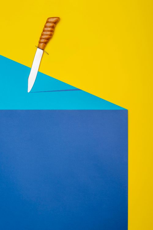 Free A knife on vibrant yellow, blue, and teal geometric papers. Abstract minimalism. Stock Photo