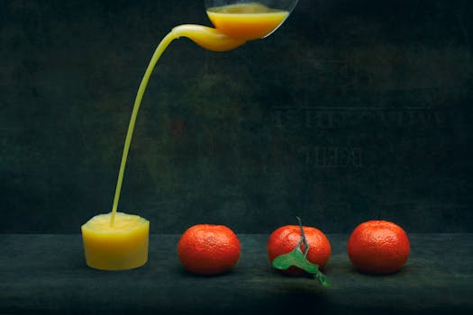 Artistic shot of fresh orange juice pouring from a glass with three oranges on a dark backdrop.