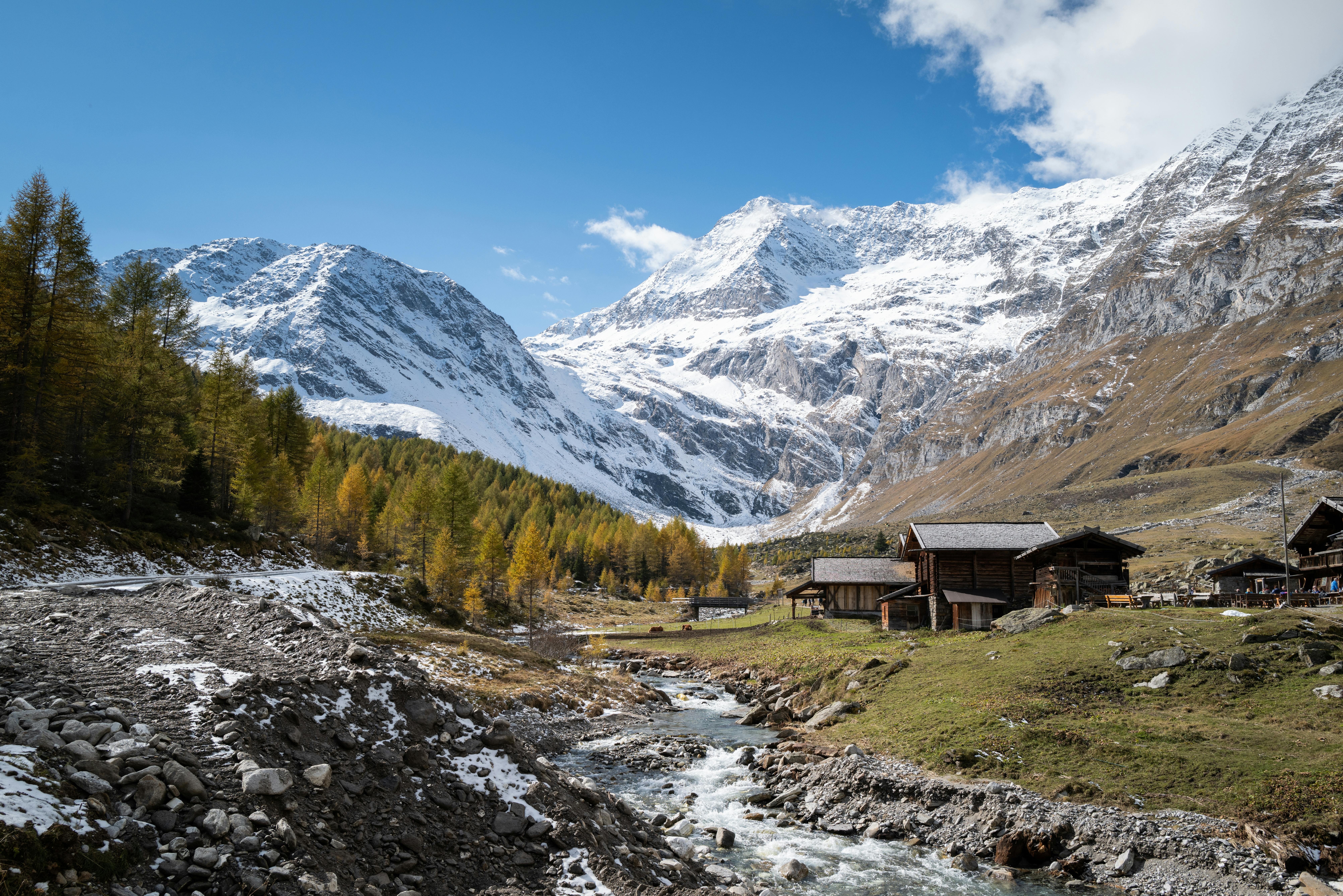 Charming alpine village with rustic cabins and snow-capped mountains under clear blue skies.
