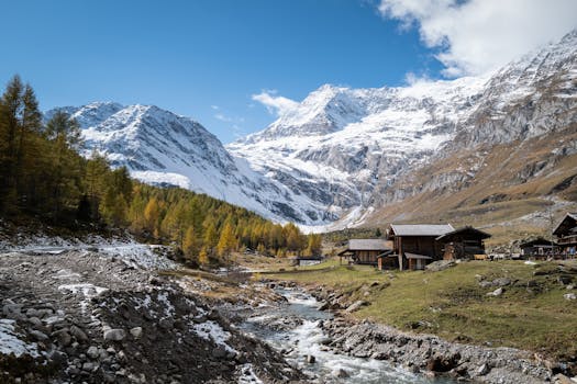 Charming alpine village with rustic cabins and snow-capped mountains under clear blue skies.