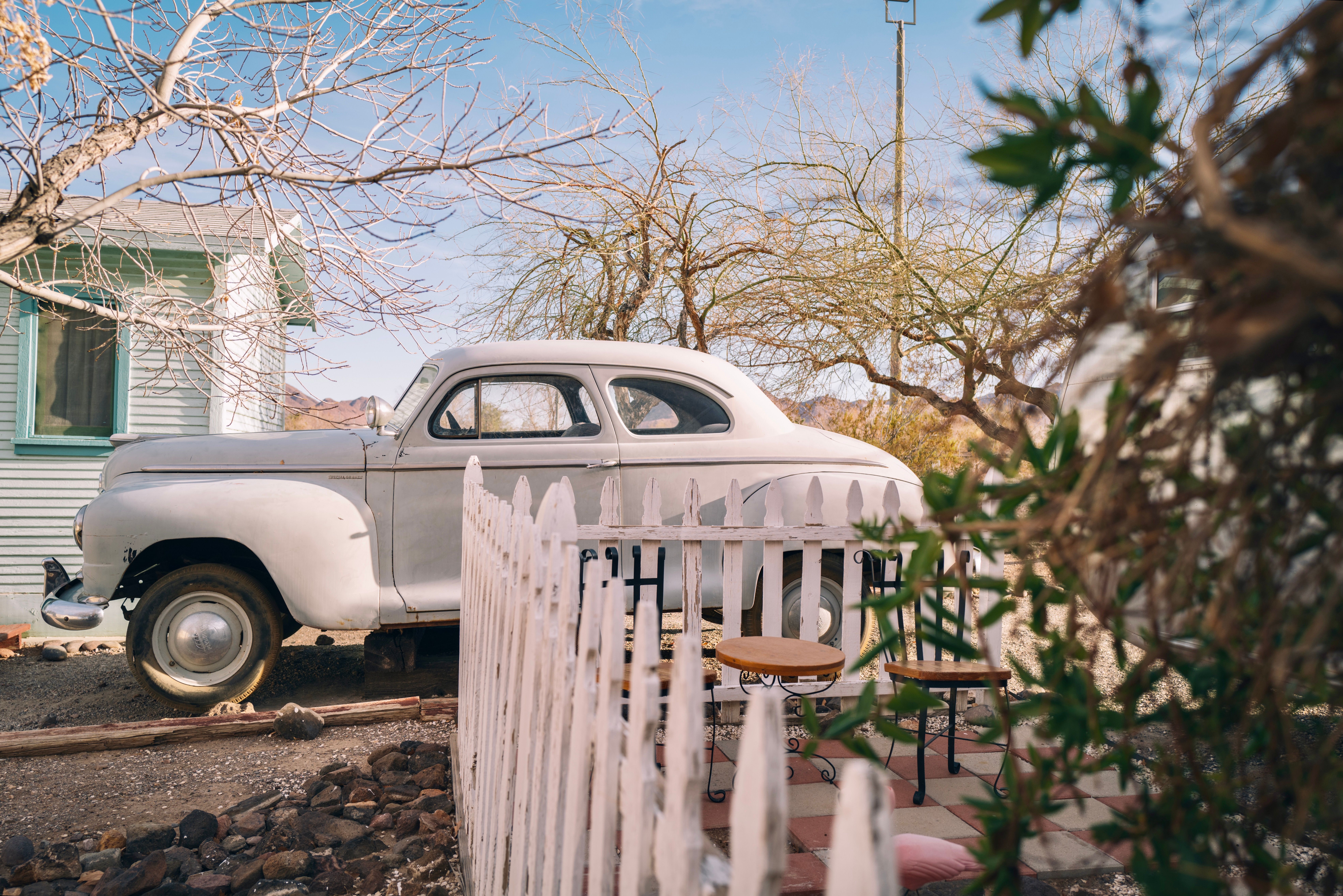 Vintage Car Parked by a Rustic House · Free Stock Photo