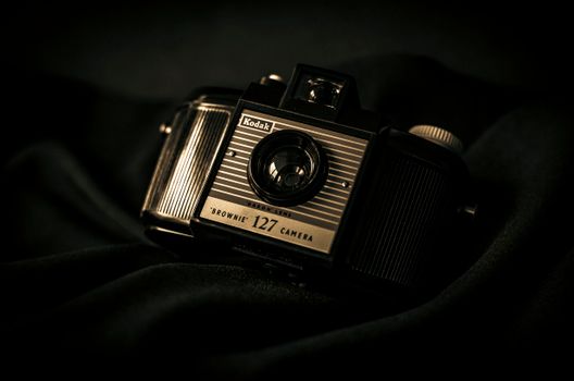 A classic Kodak Brownie 127 camera resting on a black cloth with a vintage aesthetic.