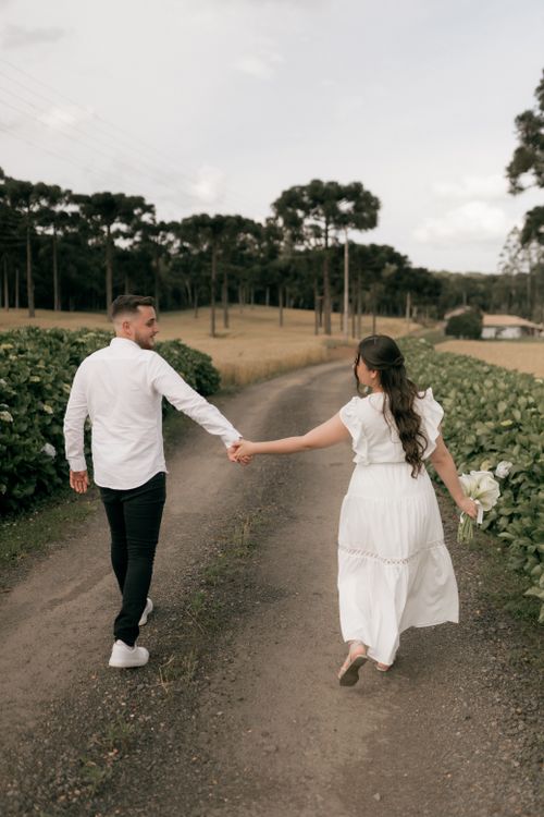 Free A couple walks hand in hand on a scenic country road in a romantic outdoor setting. Stock Photo