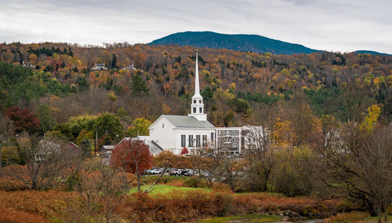 A classic New England church steeple rising above the autumn foliage