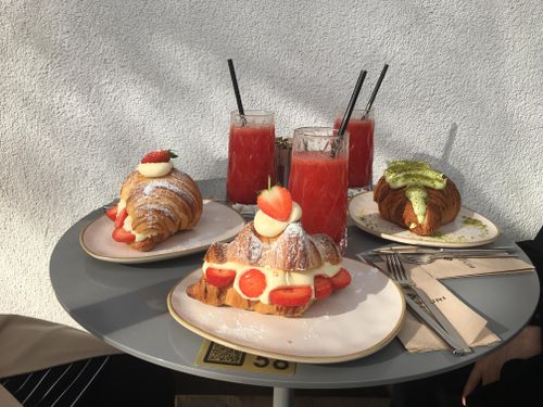 Free Tantalizing croissants with strawberries and refreshing red drinks on a sunny outdoor café table. Stock Photo