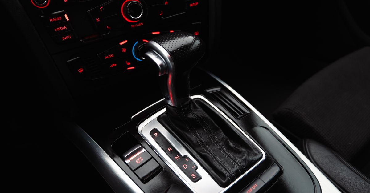 Close-up shot of a modern car gear shift lever and control panel, highlighting details.