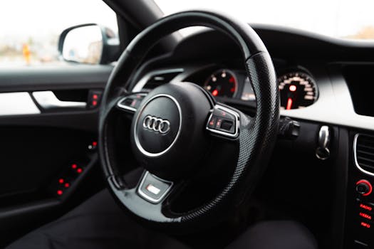 Close-up of luxury car steering wheel with dashboard and interior details, emphasizing elegance and comfort.