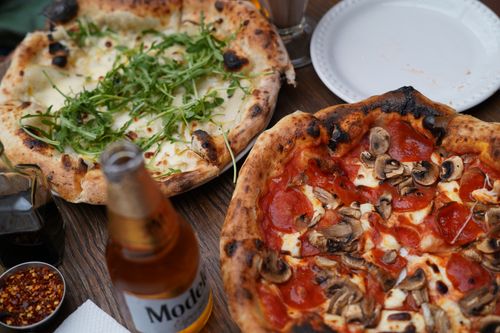 Free Two gourmet pizzas with fresh toppings on a rustic table, perfect for a cozy meal. Stock Photo