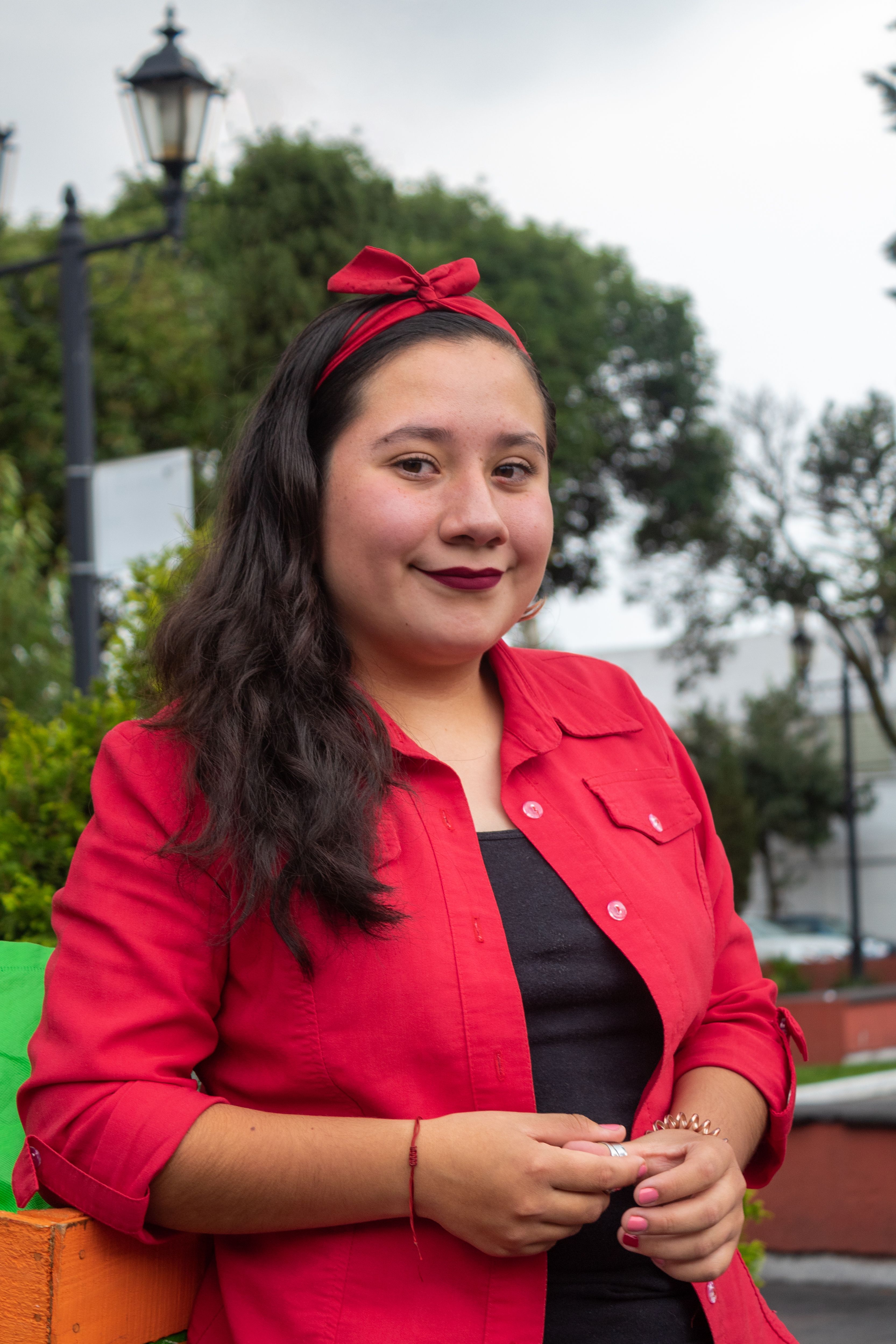 Cheerful young woman in red attire enjoying a day outdoors in a Mexican park.