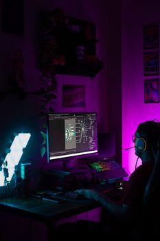 Gamer intensely focused at a neon-lit desktop setup. Vibrant and modern environment.