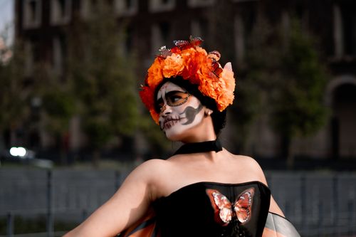Free Woman dressed for Day of the Dead in festive makeup and flower crown, adorned with butterflies. Stock Photo