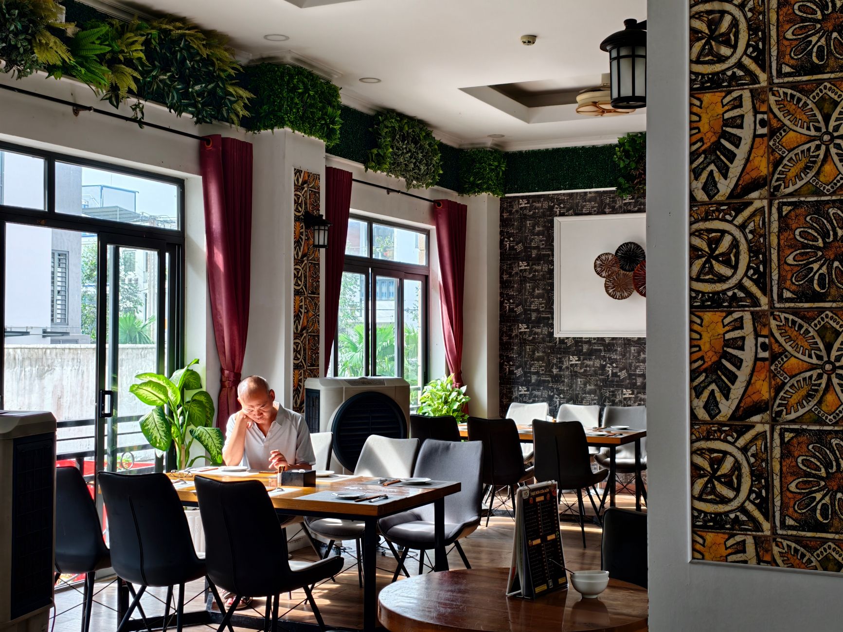 Calm restaurant setting with an adult reading and green decor.