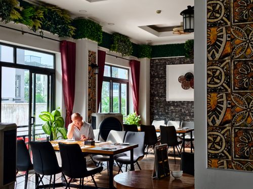 Free Calm restaurant setting with an adult reading and green decor. Stock Photo