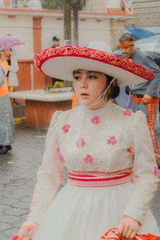A woman in colorful traditional attire attends a festive outdoor event in the rain.