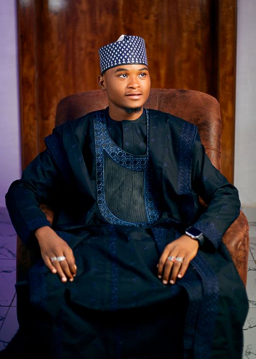 Free Portrait of an adult man wearing traditional attire and jewelry, seated indoors. Stock Photo