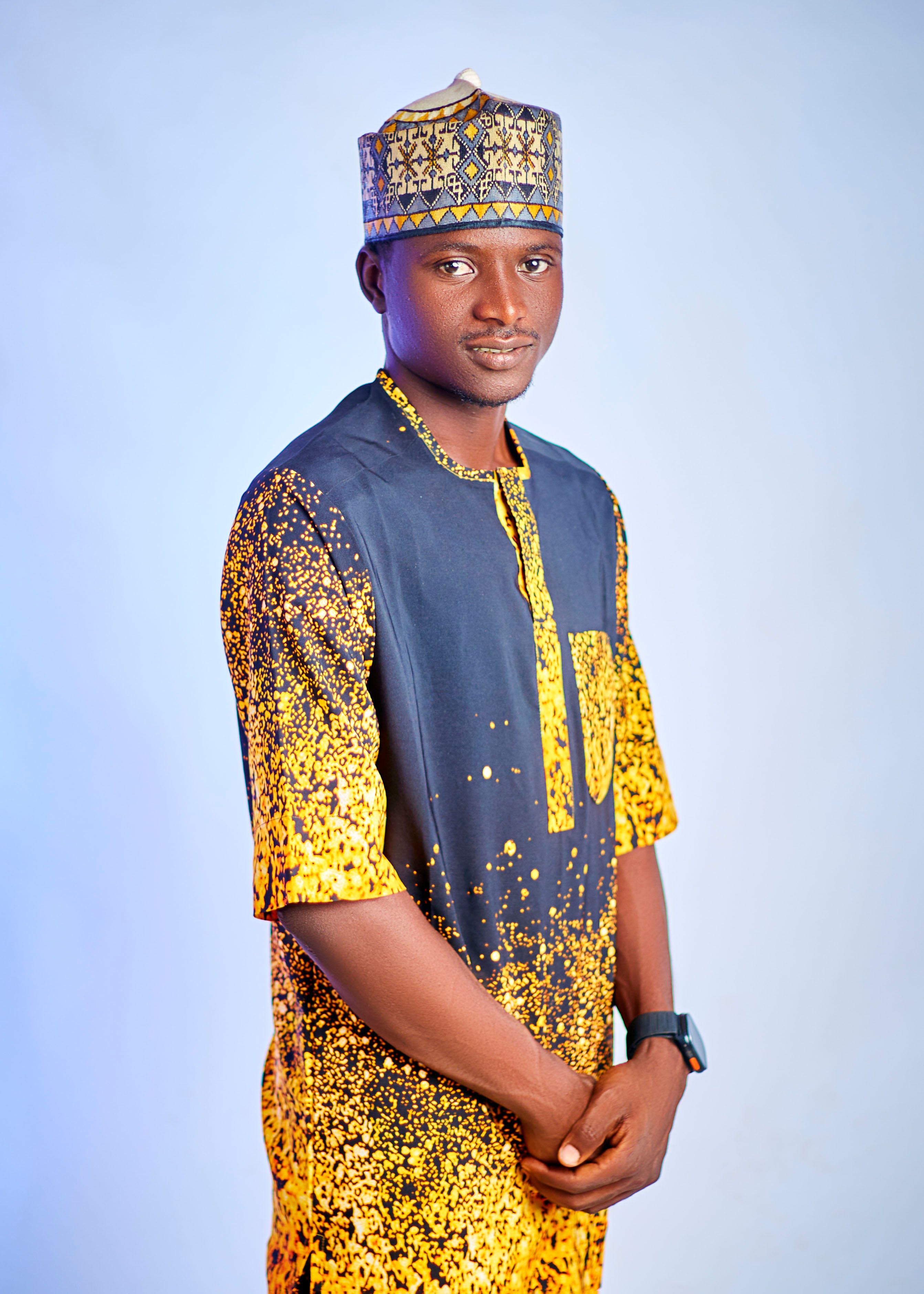 A man in colorful traditional African attire poses against a neutral background.