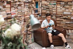 A young man enjoys reading in a leather chair surrounded by books in Ho Chi Minh City.