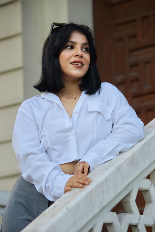 Free Young woman in white blouse posing confidently on an elegant staircase outdoors. Stock Photo